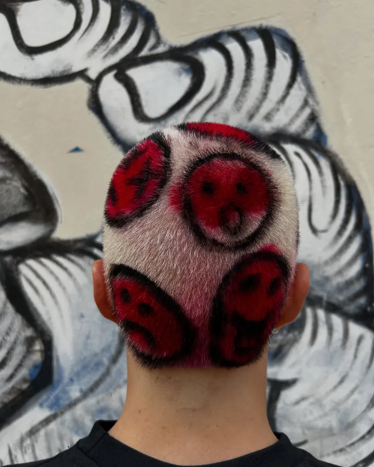 Rasato con faccine rosse disegnate sulla testa
